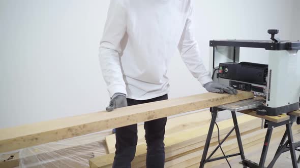 Carpenter in Protective Gloves for Working with Wood on the Planing Machine