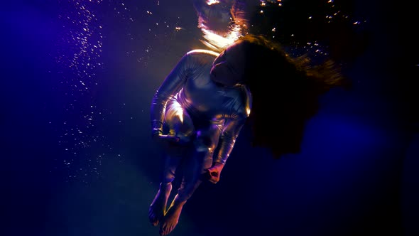 Cosmic Fantasy Woman in Metallic Suit is Diving in Depth of Sea Underwater Slow Motion Shot