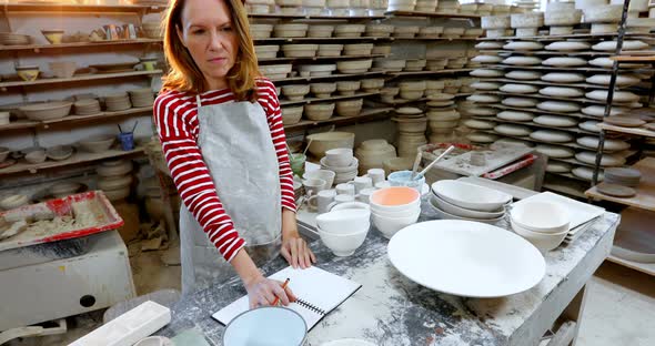 Female potter checking the orders in notebook 4k