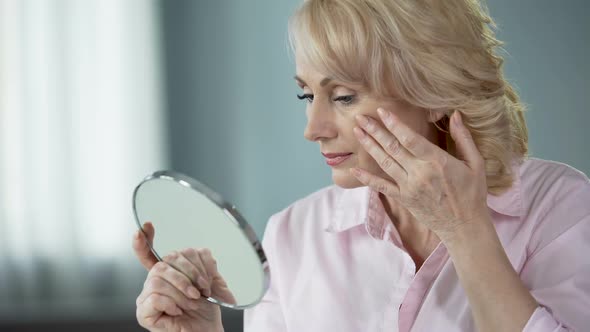 Lady Over 50 Looking at Herself in Mirror, Rejoicing at Result of Skin Lifting