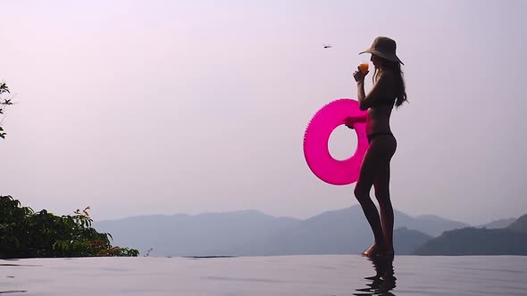 Woman Relaxing at the Edge of Infinity Swimming Pool at Resort Rubber Ring Hills and Mountain View