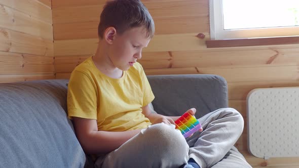 Teenage boy playing with anti-stress rainbow pop it fidget toy.