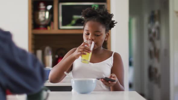 Happy caucasian lesbian couple and their african american daughter eating breakfast in kitchen