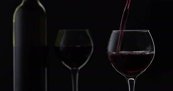 Rose Wine. Red Wine Pour in Wine Glass Over Black Background. Silhouette