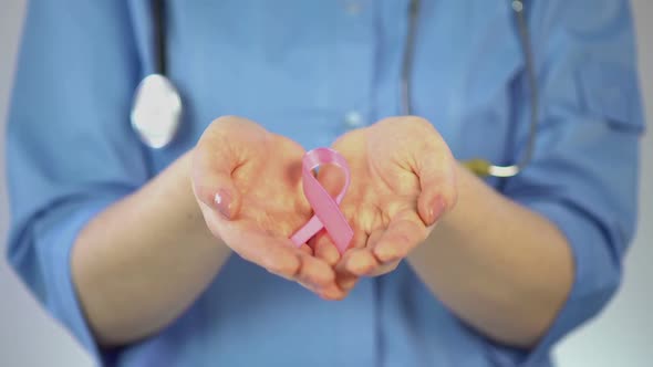 Pink Ribbon Lying in Palms of Female Doctor, Breast Cancer Awareness Campaign