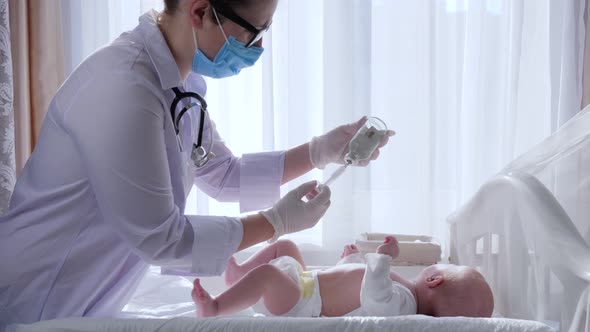 Treatment of Child, Medical Worker in Mask and Glasses Prepares Infant for Procedures