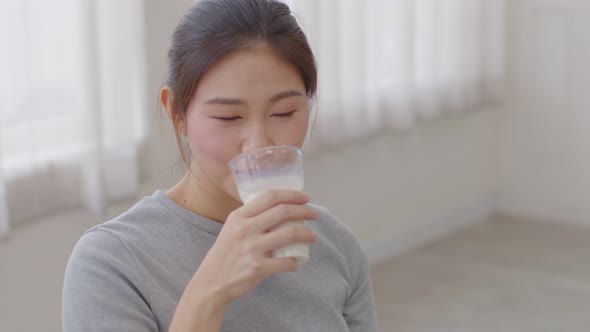 Healthy Young Asian woman Drinking milk with calcium for strong bone at home