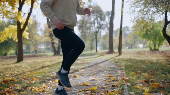 Man Doing Exercises and Stretching Before Morning Run at the Park in Autumn