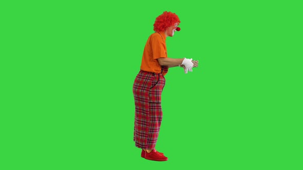 Happy Clown Holding a Box with a Gift on a Green Screen Chroma Key