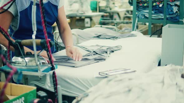 Factory Worker Is Ironing Pieces of Garment