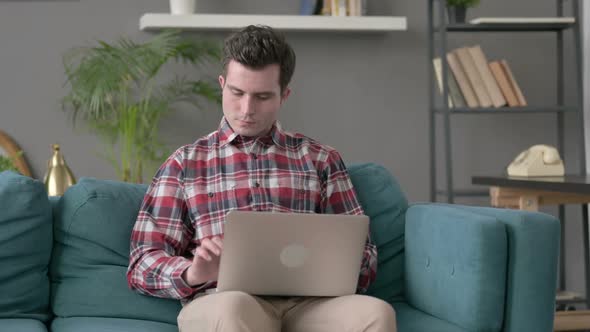 Man with Laptop Having Wrist Pain on Sofa