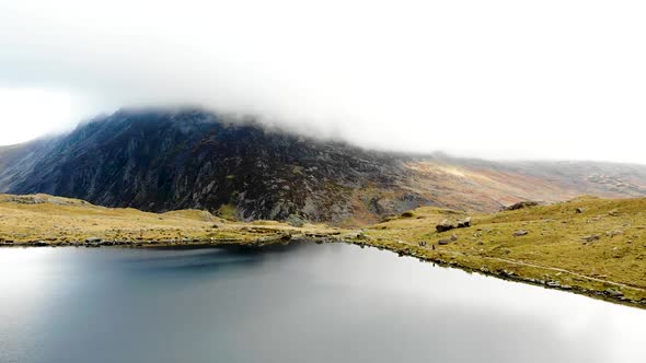 Aerial footage of rock formation and lake at Cwm Idwal, Snowdonia National Park, Wales, UK.