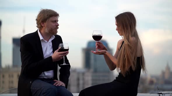 Happy Loving Couple Is Drinking Red Wine on Date on Rooftop of Big Modern City
