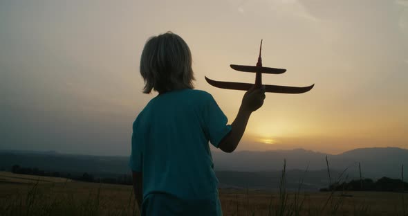 Children Stand on Field with Mountain View Holding Toy Airplane at Sunset