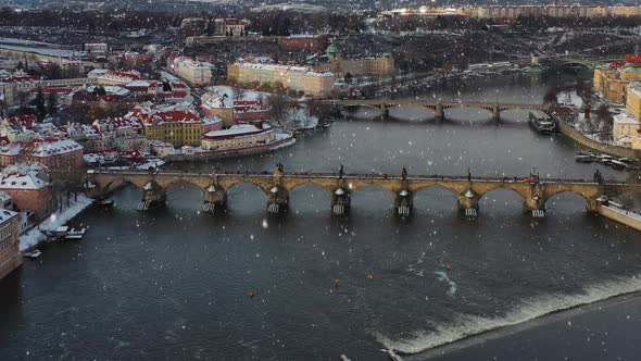 Aerial view, light snowfall on Prague, Czech Republic, Charles bridge and Vltava river on winter day