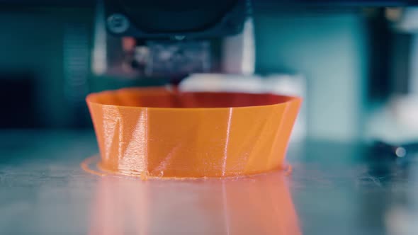 3D-printer Is Producing an Orange Object. 3D Printer Working at 3d Printing Lab.