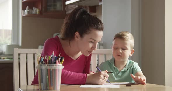 Family Time Of Mother Teaching Her Son How To Draw Sitting At The Table And Enjoying Fellowship