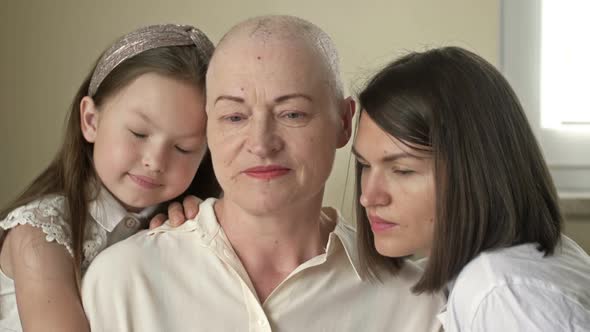 Sad Elderly Woman Bald After Chemotherapy Hugs Her Daughter and Granddaughter