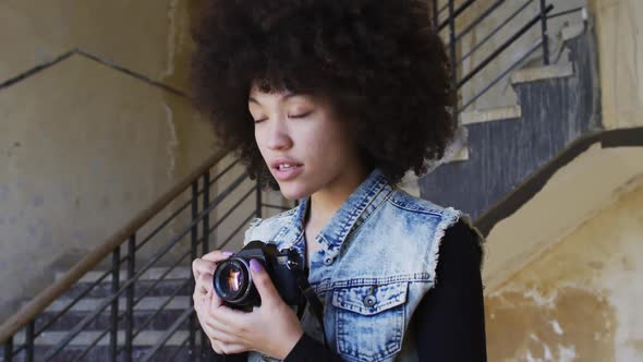 African american woman taking pictures with digital camera while standing near stairs