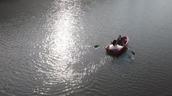 Aerial Shot of Brides Swim in a Red Boat. The Bright Sun Is Reflected in the Lake Creating a