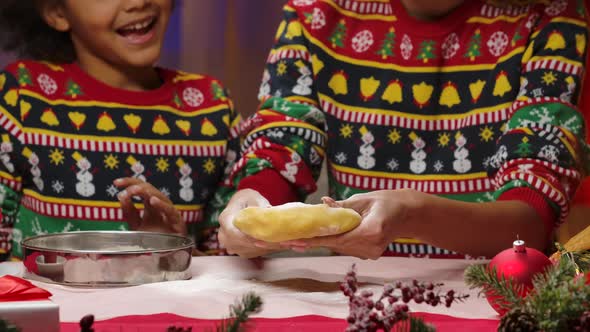 African American Mom and Little Daughter in Bright Holiday Sweaters Having Fun and Making Dough for