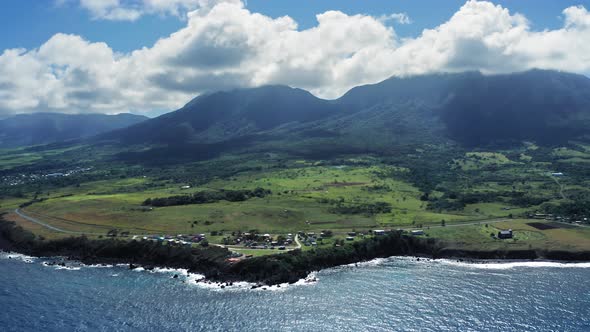 Aerial shot of Mount Liamiuga covered with tropical forests and settlement in Saint Kitts and Nevis