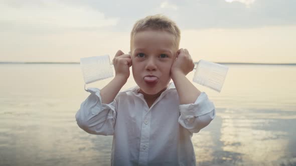 a Cheerful Child Indulges in a Pond Putting Glasses to His Ears and Grimacing