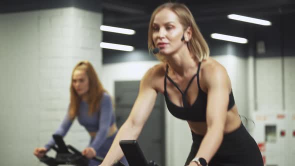 Wellness Females Training on a Spin Bikes Two Women Performs Aerobic Endurance Training on the