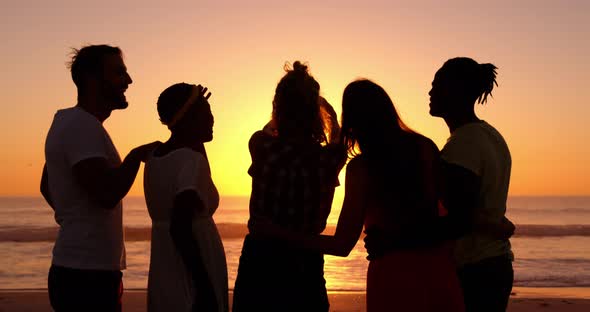 Young adult friends taking selfies on the beach at sunset 4k