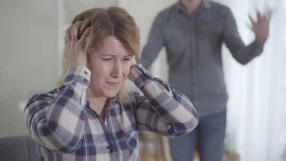 Close-up Portrait of Caucasian Woman Closing Ears with Hands and Shaking Head As Unrecognizable Man