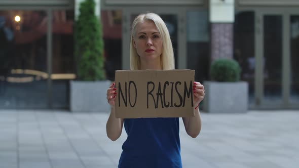 Outdoors Portrait of a Young White Female Activist Holding a Cardboard Poster with an Inscription NO