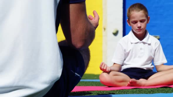 Yoga instructor instructing children in performing yoga