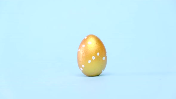 Easter Eggs are Rolling Knocking Each Other on Blue Table