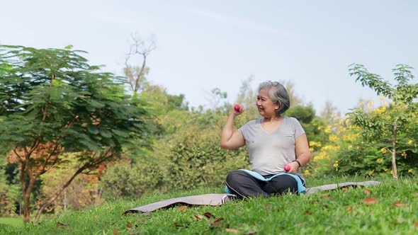 Asian elderly woman Sit and exercise in the park in the morning.