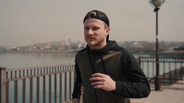 Handsome Male Athlete Is Running and Working Out on Background of Cityscape on Spring Day.