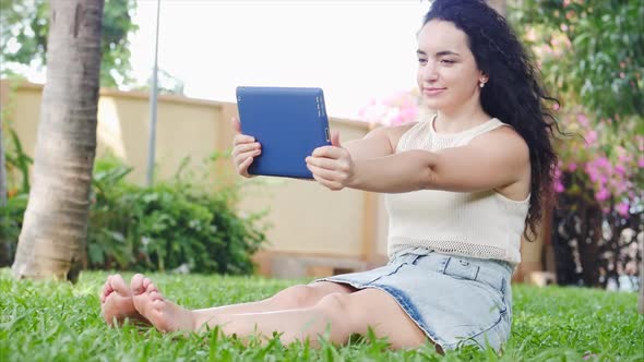 European Woman Uses a Tablet or Phone, Takes a Selfie, Plays Using the Application, Relaxing on the