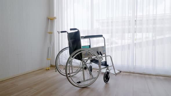 Empty modern wheelchair and walking stick or canes in hospital room.