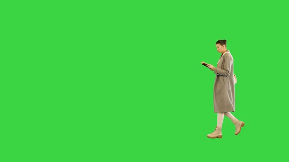 Young Woman in Stylish Clothes Walks Reading a Book on a Green Screen Chroma Key