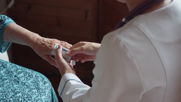 Medicine Age Health Care and People Concept  Doctor Checking Senior Woman Pulse at Home