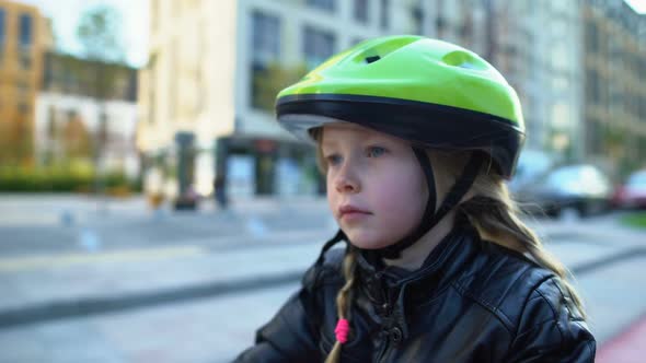 Attentive Little Girl in Sports Helmet Sitting on Bicycle, Ready to Ride Outdoor