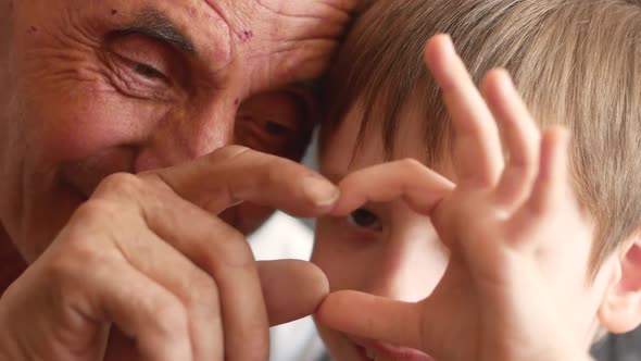 The grandson and grandfather show a heart gesture with the help of their hands