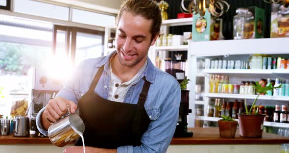 Smiling waiter making cup of coffee at counter