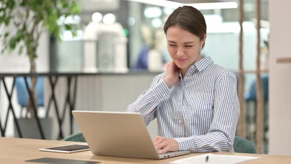 Tired Young Woman with Laptop Having Neck Pain in Office 