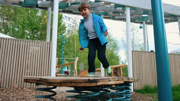 A Little Boy Playing on the Outdoors Playground - Jumping on the Stand on the Springs