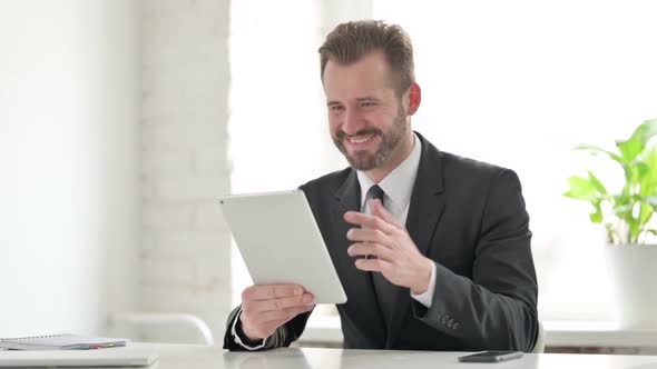 Young Businessman Celebrating Success on Tablet in Office
