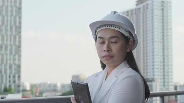 A confident female architect in a white hat looks at the camera with a smile.