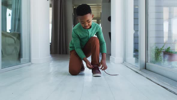 African american boy standing in hallway tying his shoes