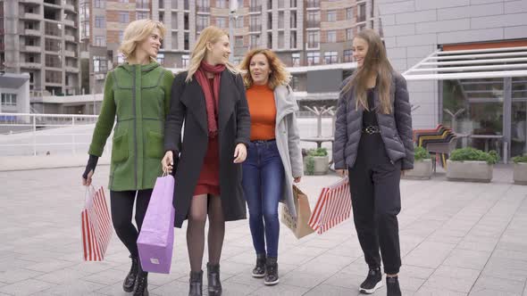 Four Beautiful Girlfriends Walking on the Street Talking Happily. Four Fashion Women with Shopping
