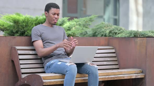 Upset Young African Man Reacting to Loss on Laptop on Bench