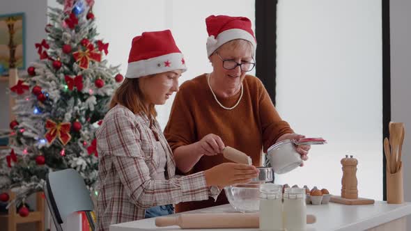 Grandmother Putting Flour Ingredients in Strainer Explaining to Granddaughter